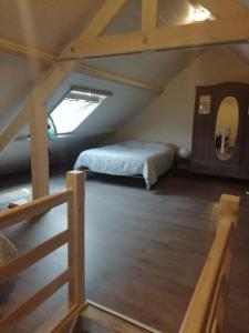 - une chambre mansardée avec un lit et une fenêtre dans l'établissement Gîte Ferme d'hurtaux, à Froidchapelle