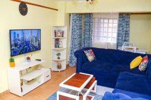 a living room with a blue couch and a tv at Lovely One bedroom Apartment , TRM Drive Nairobi in Nairobi