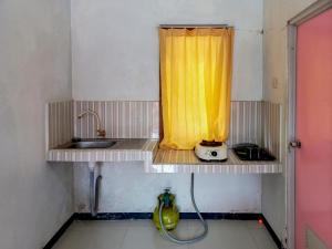 a kitchen with a sink and a yellow curtain at Villa Kampoeng City Pacet Mitra RedDoorz in Mojokerto