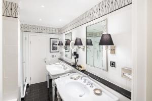 a bathroom with two sinks and two mirrors at Fairmont Hotel Vier Jahreszeiten in Hamburg