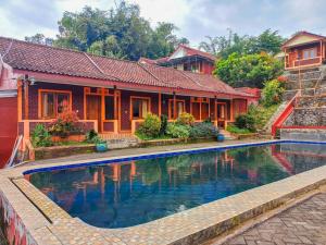 a house with a swimming pool in front of it at Villa Kampoeng City Pacet Mitra RedDoorz in Mojokerto