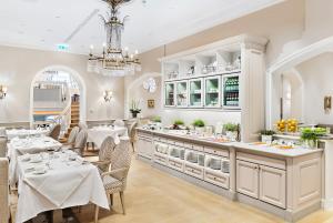 a restaurant with tables and chairs and a chandelier at Fairmont Hotel Vier Jahreszeiten, Hotel des Jahres 2023 & 2024- Die 101 Besten in Hamburg