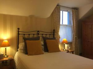 a bedroom with a bed with two lamps and a window at Glendale Guest House in Keswick