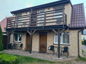 a house with a deck with chairs and a table at Apartamenty rodzinne U Zośki in Łukęcin