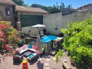 um quintal com uma piscina e cadeiras e um guarda-sol em L'apartement deluxe em Azille