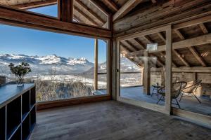 Una habitación con una gran ventana con una mesa y sillas. en Chalet Chèvrefeuille, en Saint-Gervais-les-Bains