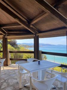 een tafel en stoelen op een patio met uitzicht op de oceaan bij HOTEL A RENA D'ORU in Coggia