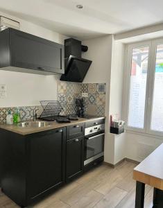 a kitchen with black cabinets and a sink at Charmant studio au coeur du centre ville in Chagny