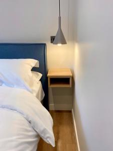 a bed with a blue headboard and a wooden night stand at Hygge at Vallum in Newcastle upon Tyne