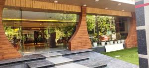 budynek z dużymi szklanymi oknami z roślinami w obiekcie Hotel Sakura by Maps w mieście Gurgaon