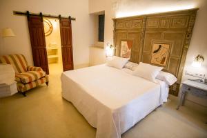 a bedroom with a large white bed and a chair at Apartamentos Sharis in Jerez de la Frontera