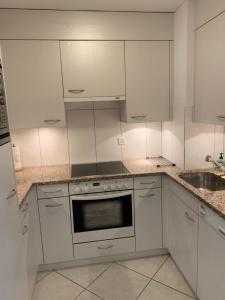eine weiße Küche mit weißen Schränken und einem Waschbecken in der Unterkunft Apartment Flims Waldhaus - Surselvapark A4 in Flims