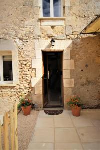 an entrance to a stone building with two potted plants at Joli gîte pour 5 personnes : Chez Cherrie in Saint-Julien-de-Lampon