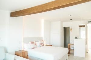 um quarto com uma cama branca e almofadas cor-de-rosa em Hotel Boutique & Spa Las Mimosas Ibiza em Baía de San Antonio