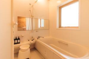 een badkamer met een bad, een toilet en een wastafel bij Sea Forest 南熱海 in Atami