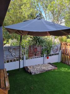 an umbrella sitting on the grass next to a fence at Dolphins Self-Catering Accommodation in George