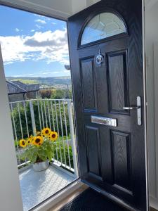 een zwarte deur met een raam en een vaas met bloemen bij Moll’n’Cliff in Silsden