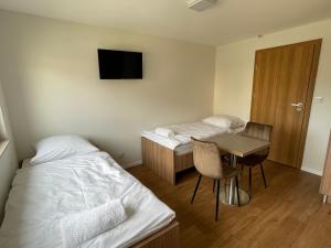 a room with two beds and a desk and a tv at Apartmotel ANROE in Chminianska Nová Ves