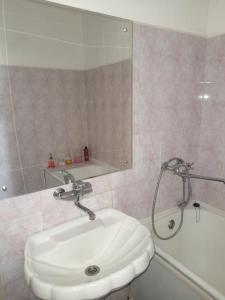 a bathroom with a white sink and a bath tub at Изумруд in Uralsk