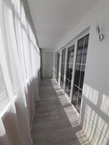 a hallway with white walls and windows in a building at Изумруд in Uralsk