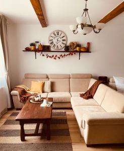 uma sala de estar com um sofá e um relógio na parede em Várárok Vendégház - Miskolc em Miskolc