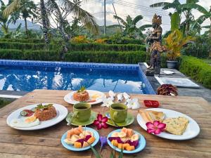 a table with plates of food next to a pool at RR Cottage in Nusa Penida