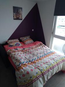a bed with a colorful comforter in a bedroom at Studio-Cosy 2 vue port à deux pas de Nausicaa in Boulogne-sur-Mer
