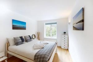 a white bedroom with a bed and a window at Lovely 2 bedroom flat overlooking Canary Wharf in London