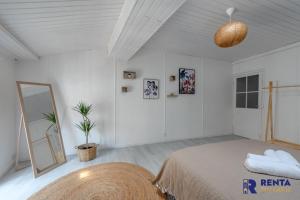 a white bedroom with a bed and a mirror at Le MéditerranéenWIFI6 personnes in Saint-Cyprien