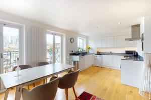a kitchen with white cabinets and a table and chairs at Lovely 2 bedroom flat overlooking Canary Wharf in London
