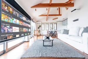 ein Wohnzimmer mit einem Sofa und einem TV in der Unterkunft Villa Sunshine in Ito