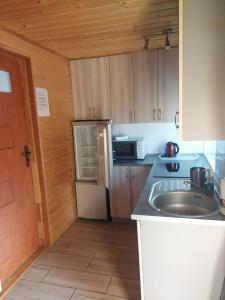 a small kitchen with a sink and a refrigerator at Siedlisko na Zaciszu domek in Kąty Rybackie