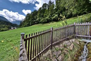 Ein Holzzaun auf einem Feld neben einem Hügel in der Unterkunft Ferienwohnung Berghäusl in Bischofswiesen