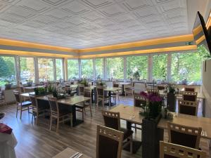 ein Restaurant mit Tischen, Stühlen und Fenstern in der Unterkunft Hotel am Westend in Lahr