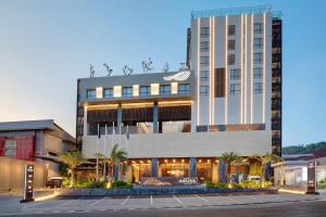 a large building with palm trees in front of it at Hotel Aruss Semarang in Semarang