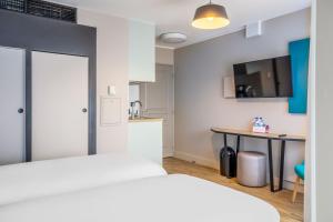 une chambre avec un lit et une table et une cuisine dans l'établissement Appart'City Confort St Quentin en Yvelines - Bois D'Arcy, à Bois-dʼArcy