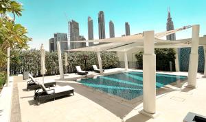 einen Pool mit Sonnenschirmen und Stühlen neben einem Gebäude in der Unterkunft Elite Royal Apartment - Panoramic Full Burj Khalifa, Fountain & Skyline View - ACed direct connection to Dubai Mall - Governor in Dubai