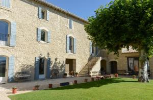 un gran edificio de piedra con un árbol delante de él en La Bastide Neuve, en Joucas