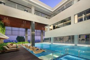 an indoor pool in a building with lounge chairs at Hotel Aruss Semarang in Semarang