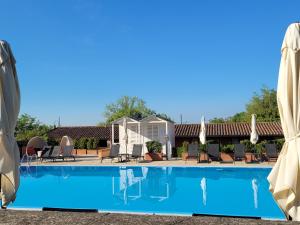 una piscina con sillas y sombrillas en un complejo en Relais Sant'Uffizio Wellness & Spa, en Cioccaro