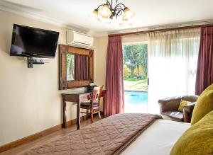 a hotel room with a bed and a desk and a television at Sunward Park Guest House & Conference Center in Boksburg