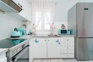 a white kitchen with a sink and a refrigerator at yiayia and papou Luxury House in Limenas