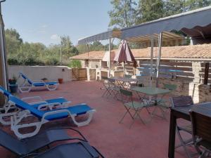 eine Terrasse mit Stühlen, Tischen und einem Sonnenschirm in der Unterkunft Chambres d'hôtes "La Source" in Mareuil-sur-Lay