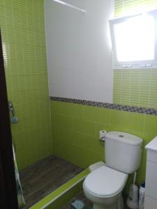 baño de azulejos verdes con aseo y ventana en CasaMaria 50 metros de la playa, en El Palmar