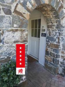 a door to a stone building with a red and white sign at Llys Bach Apartment at Llys Aeron in Aberaeron