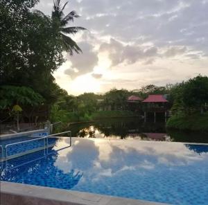 a pool at the resort with a reflection in the water at Api-api Eco Chalet in Pantai Kok