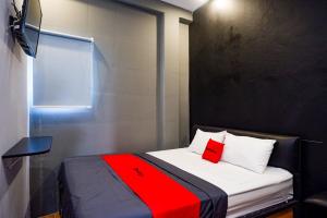 1 dormitorio pequeño con 1 cama con manta roja en RedDoorz @ Jalan Raya Baturaden 2, en Rempawah