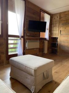 a living room with a ottoman and a flat screen tv at Incantevole appartamento stile chalet Breuil Cervinia in Breuil-Cervinia