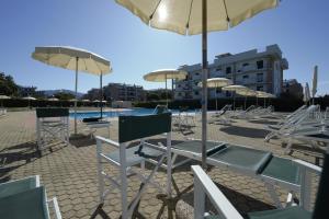 a group of chairs and umbrellas next to a pool at Le Residenze di Santa Costanza - Mirto/Corbezzolo in San Vincenzo