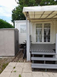ein Haus mit einer Veranda und einer Holzterrasse in der Unterkunft Mobil home camping les écureuils in Mimizan